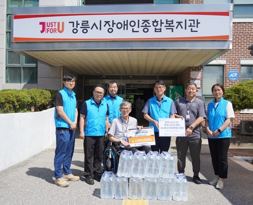 국토안전관리원 강원지역본부 관계자들이 강릉 사천면에 위치한 장애인복지시설에 생수를 전달하고 기념촬영하고 있다.